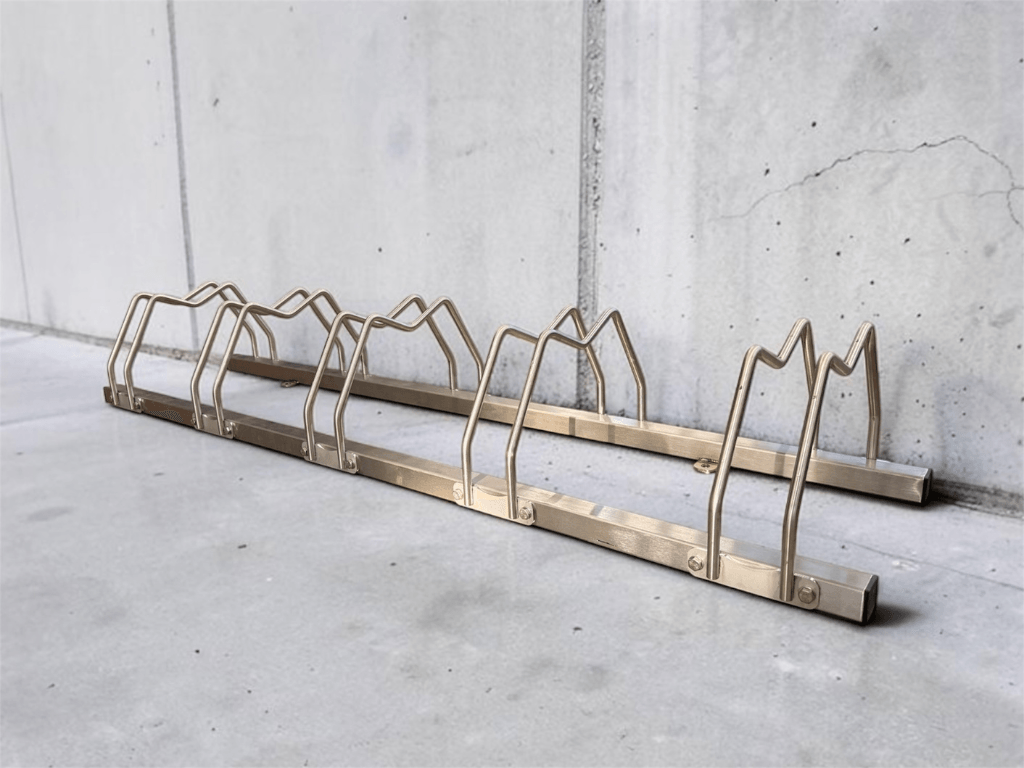 Rastrelliera bici a 5 posti in acciaio inox 304 installata all'esterno su pavimentazione in cemento, ideale per condomini.